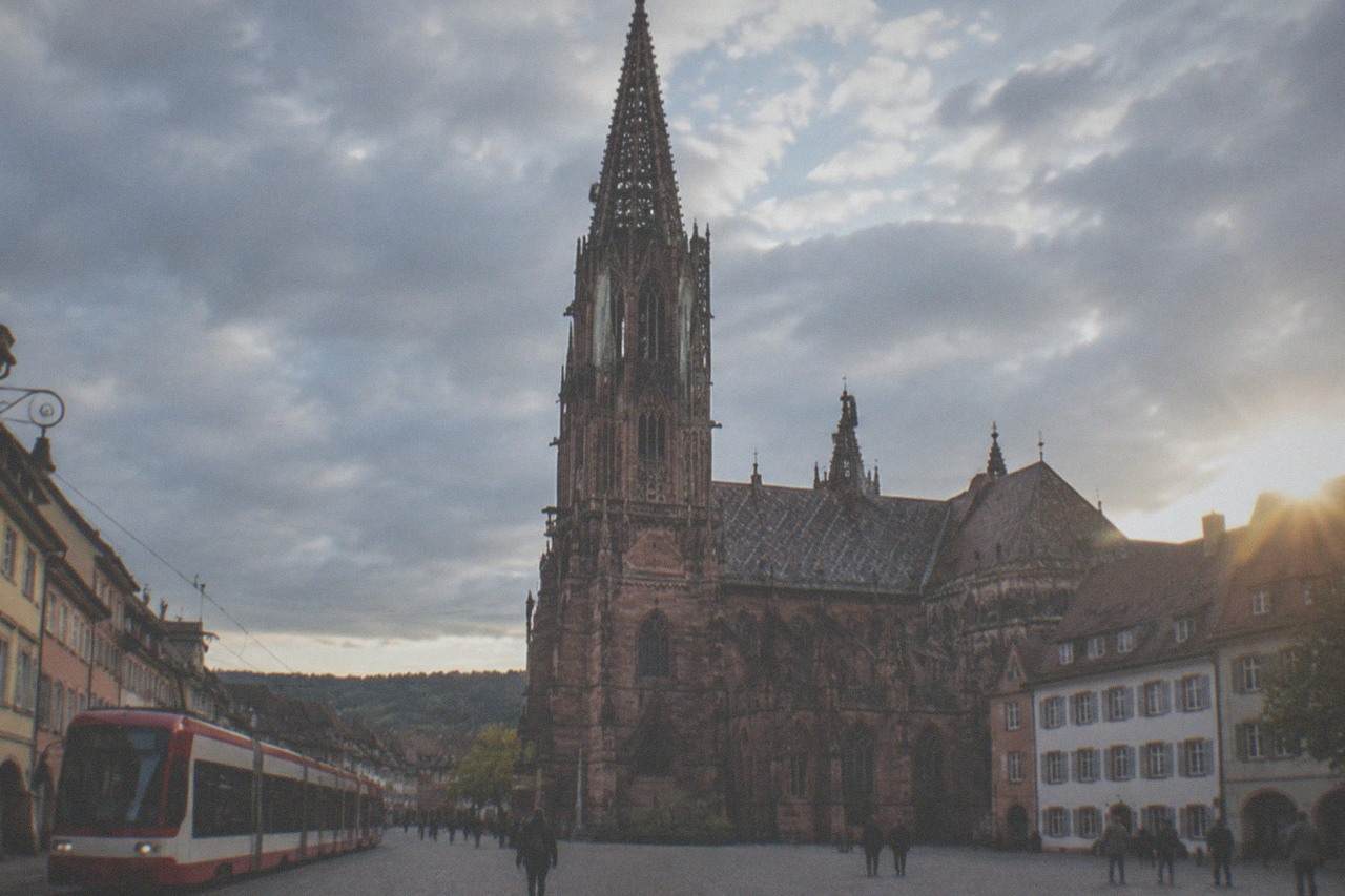 A red and white Freiburg tram passing historic buildings on a narrow old town street