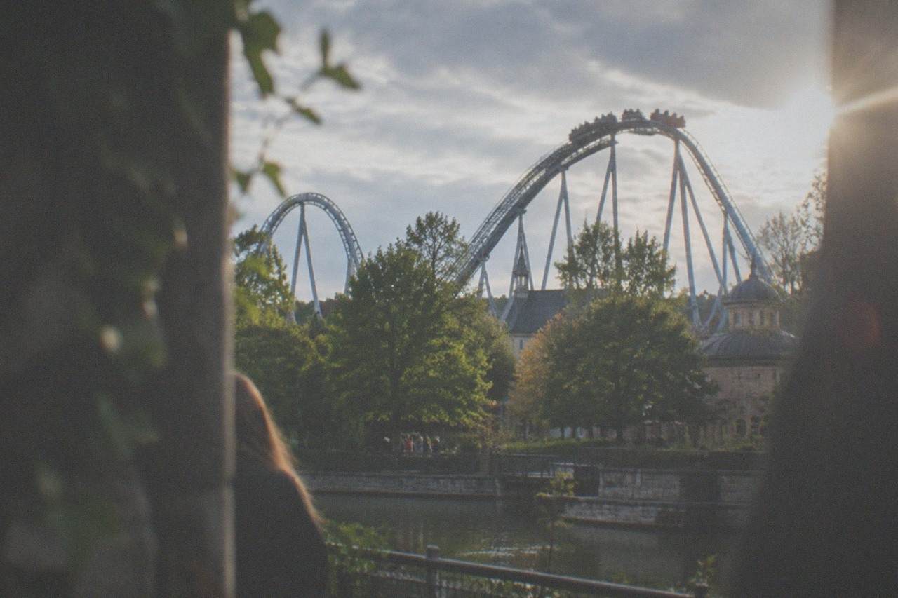 Roller coaster tracks rising above the treeline at a large amusement park on a sunny day