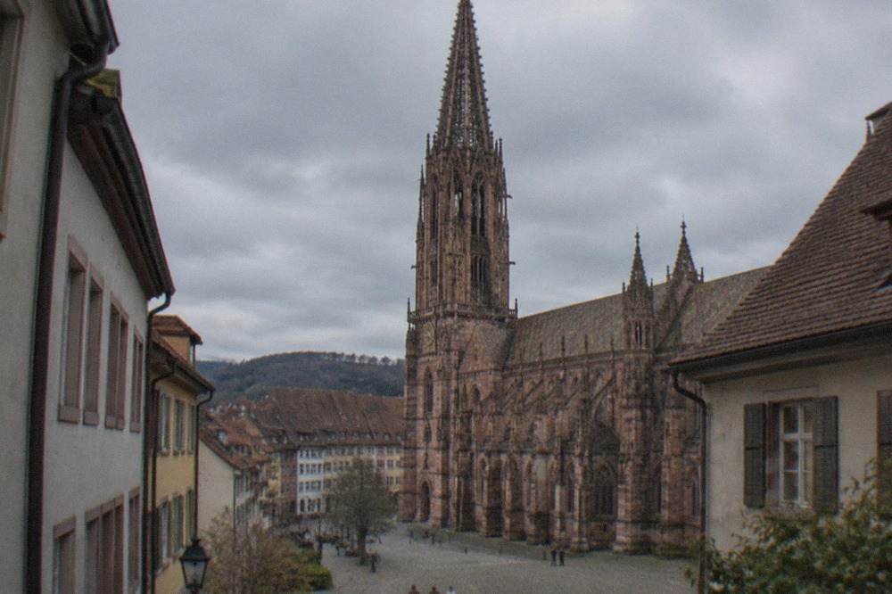 Gothic stonework and spire of Freiburg Minster seen from a narrow old town lane