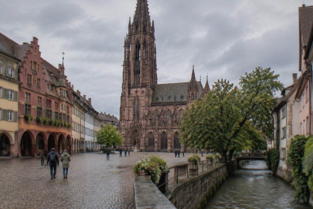 Cobbled square in Freiburg with historic guild houses and a stream running along the street