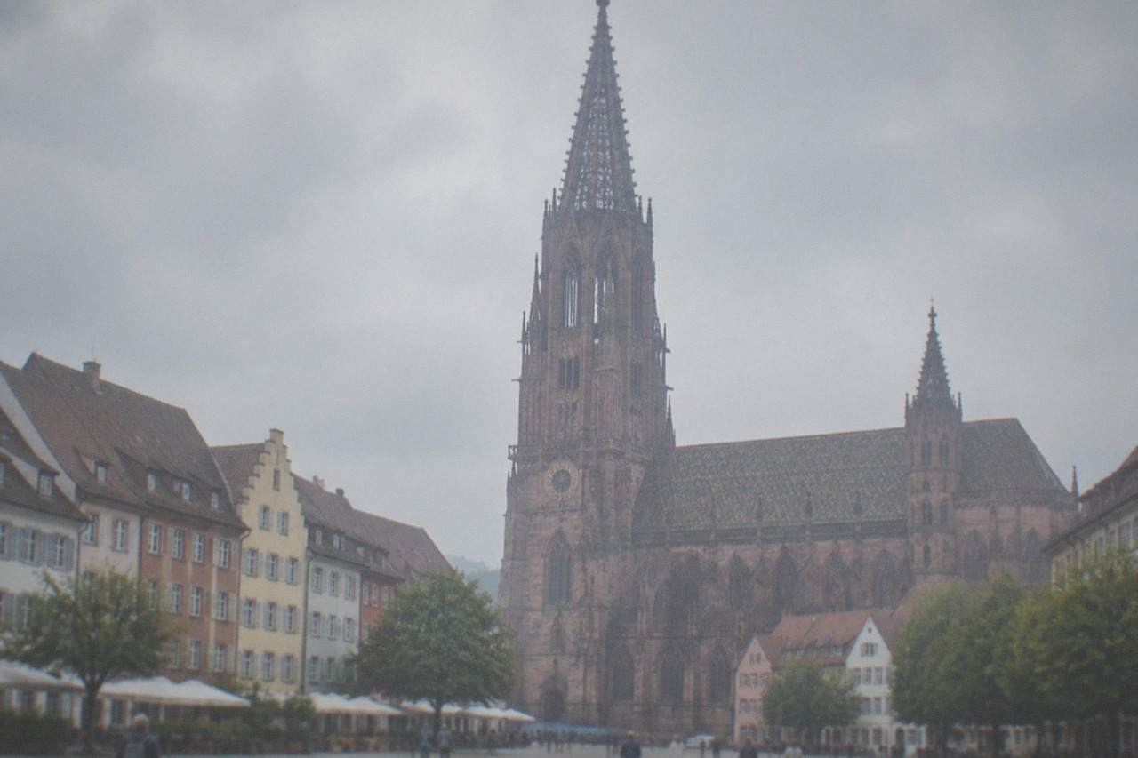 Cobblestone square with a gothic cathedral tower rising above rows of gabled old town houses