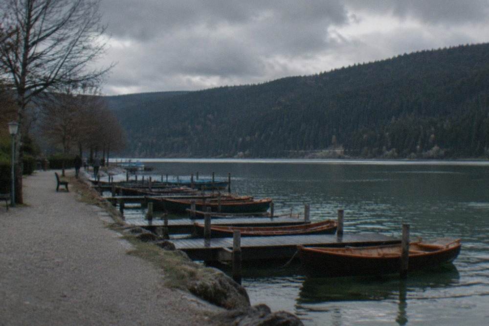 A wide mountain lake with dark forest slopes rising from the far shore