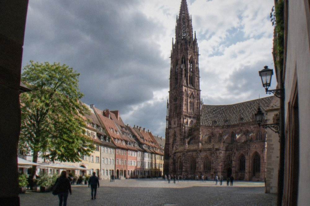 Freiburg old street with the Minster tower rising above red rooftops