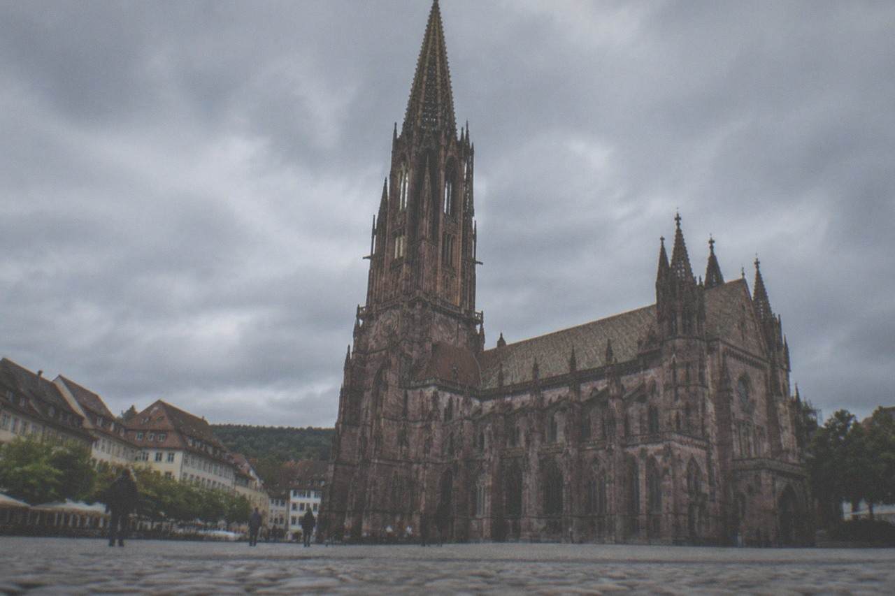 Historic old town rooftops and a Gothic cathedral tower rising above a green valley city
