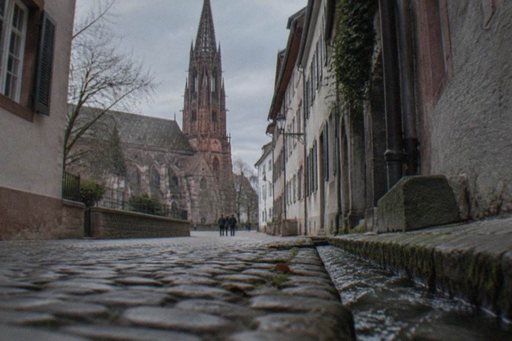Narrow medieval lane in Freiburg with small water channels running along the cobbles