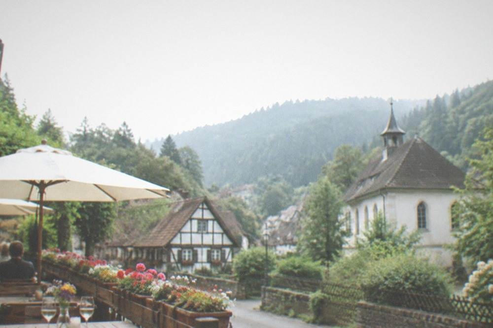 small tavern terrace with wooden tables, wine glasses and flower boxes on a Günterstal street