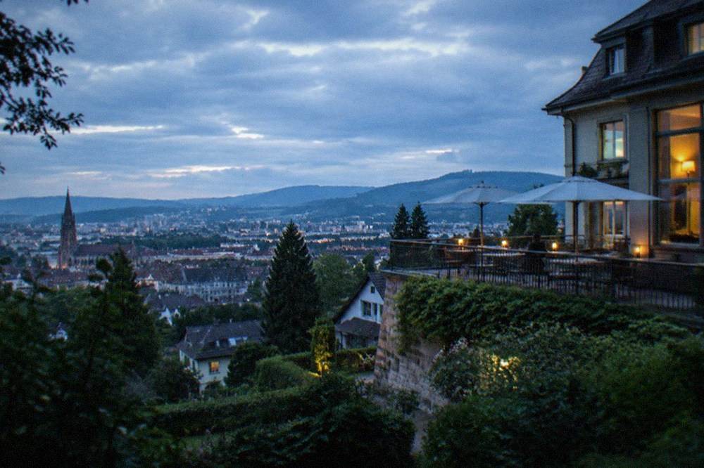 A hilltop hotel building with a panoramic terrace above a city skyline