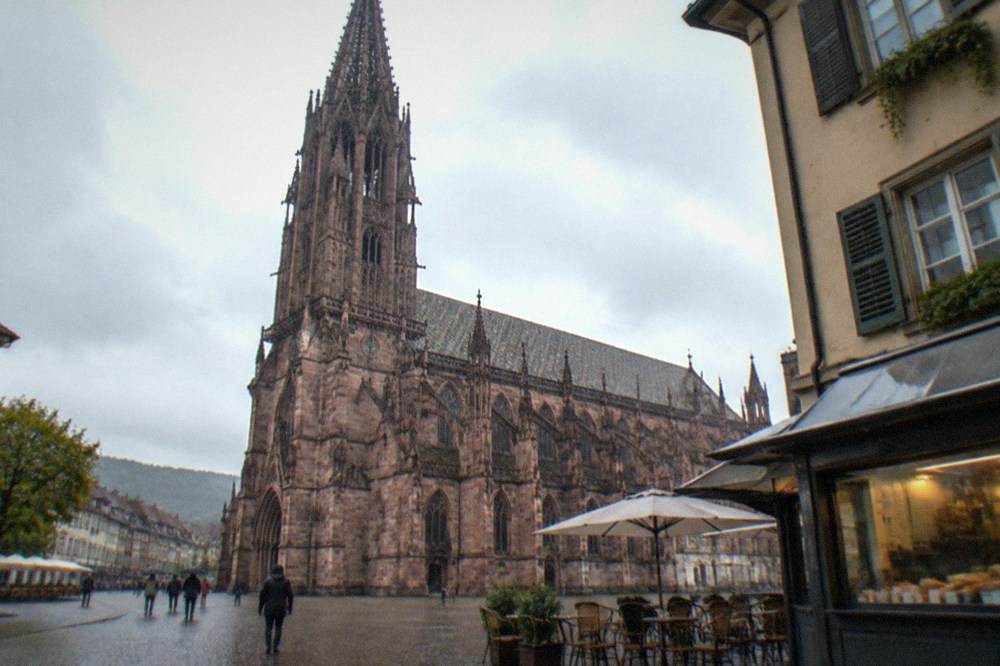 Small café tables and a kiosk window on a corner street in a Freiburg residential district
