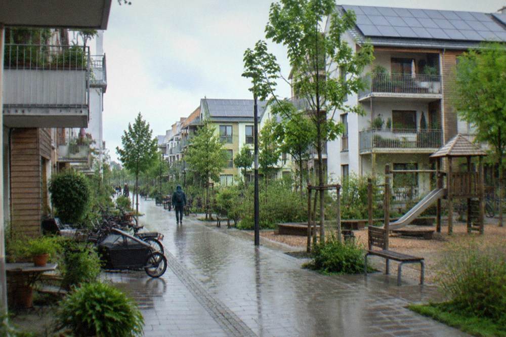 Pedestrian street between houses with balconies, planters and children's play area