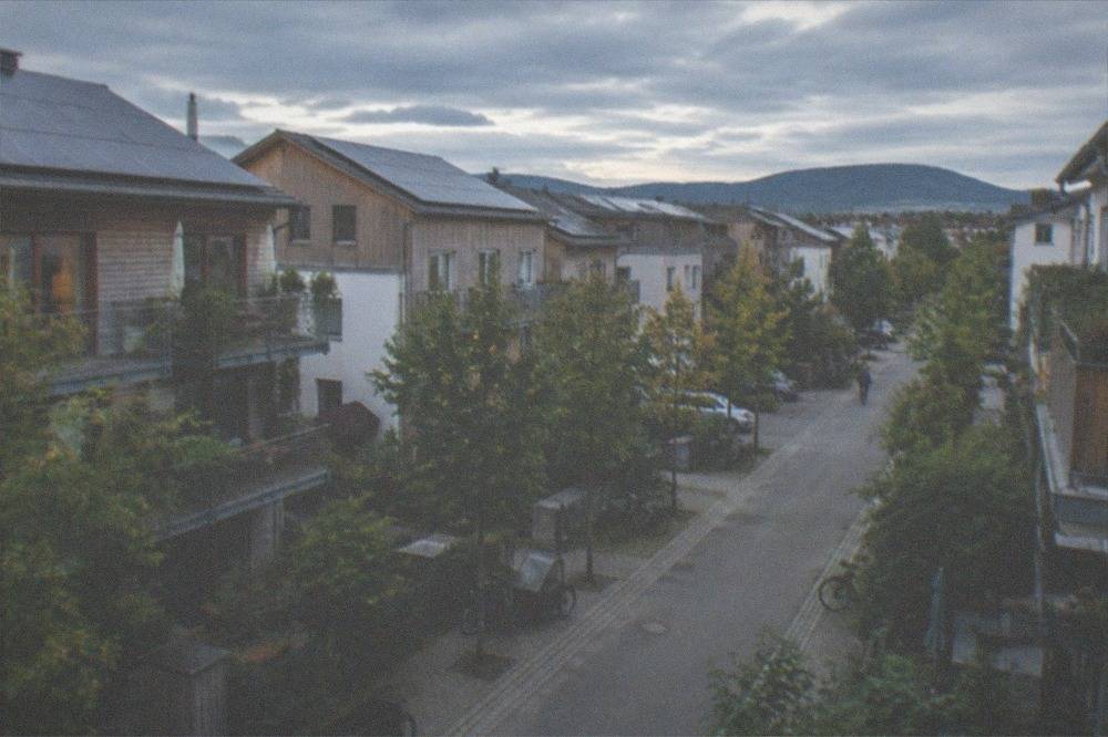 Quiet residential street with row houses, front gardens and parked bicycles in evening light