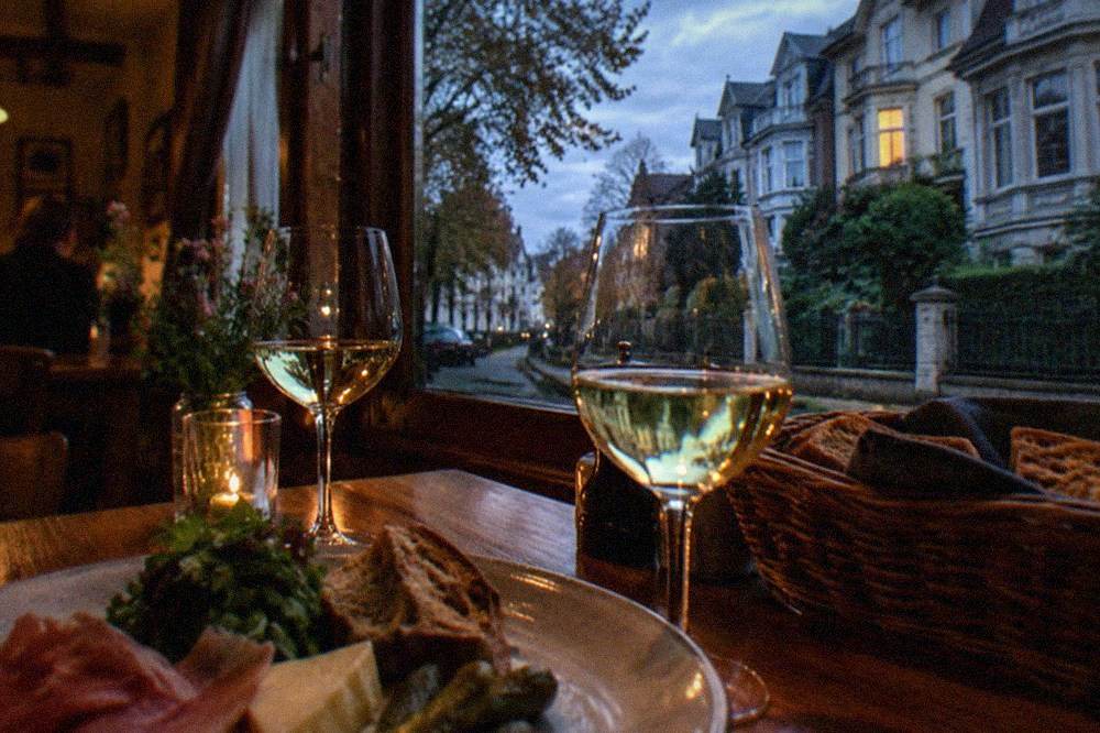 Table set with wine glasses and regional food inside a cozy tavern