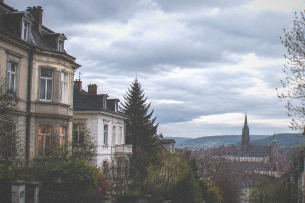 Evening view over relaxed neighborhood rooftops toward a distant old town skyline