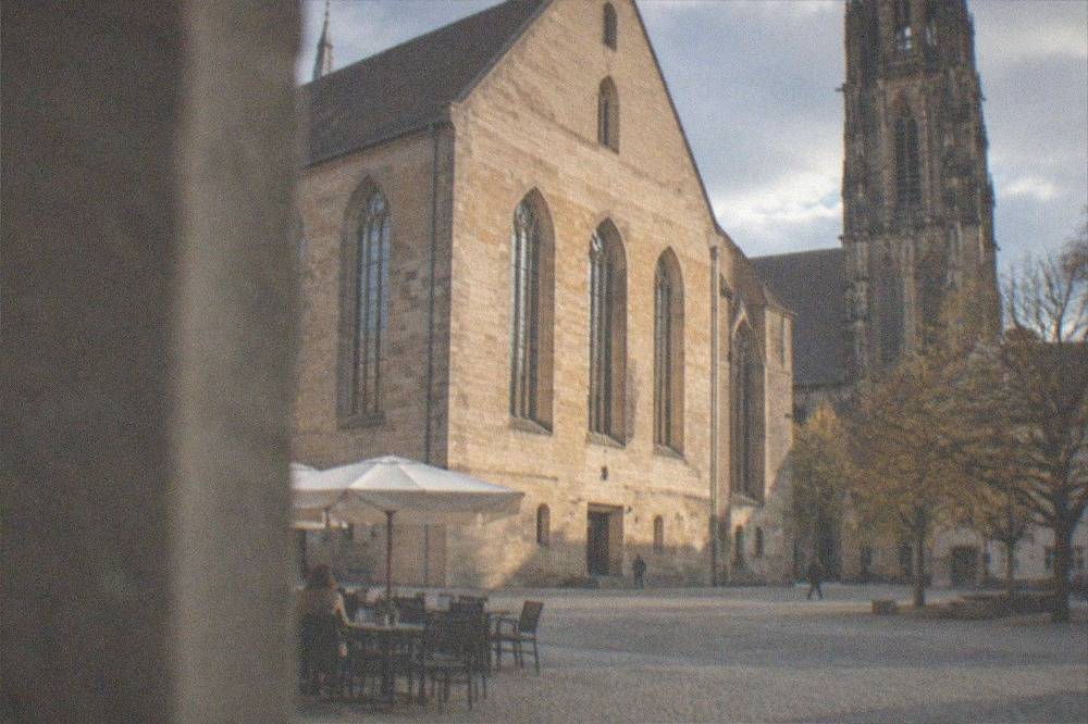 Café tables on a cobblestone square beside a historic church tower