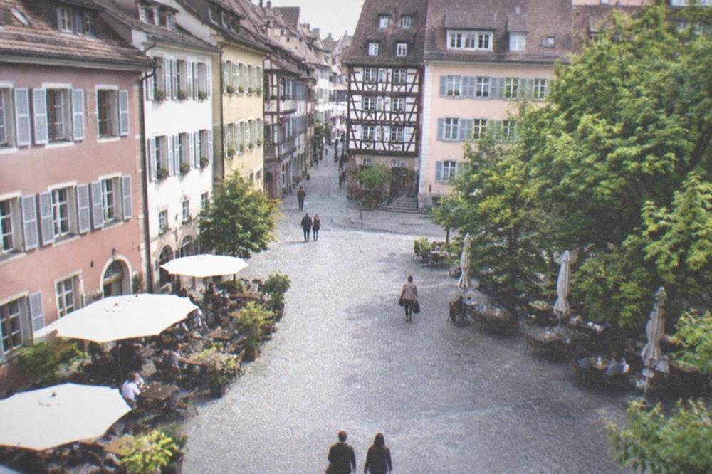 Old town street with half-timbered facades opening into a small square in evening light