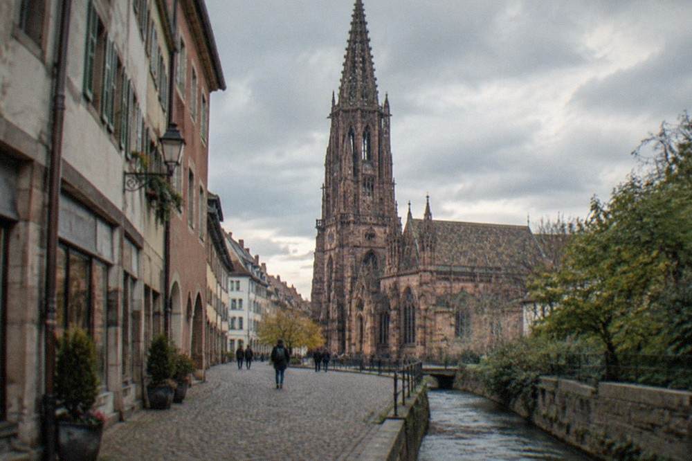A street corner in Freiburg old town with a small water channel running beside the pavement and old shopfronts