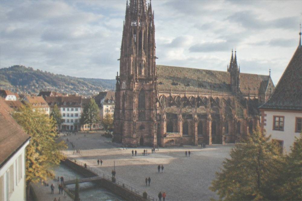 A sunny square in Freiburg with people walking beside a small street-level water channel