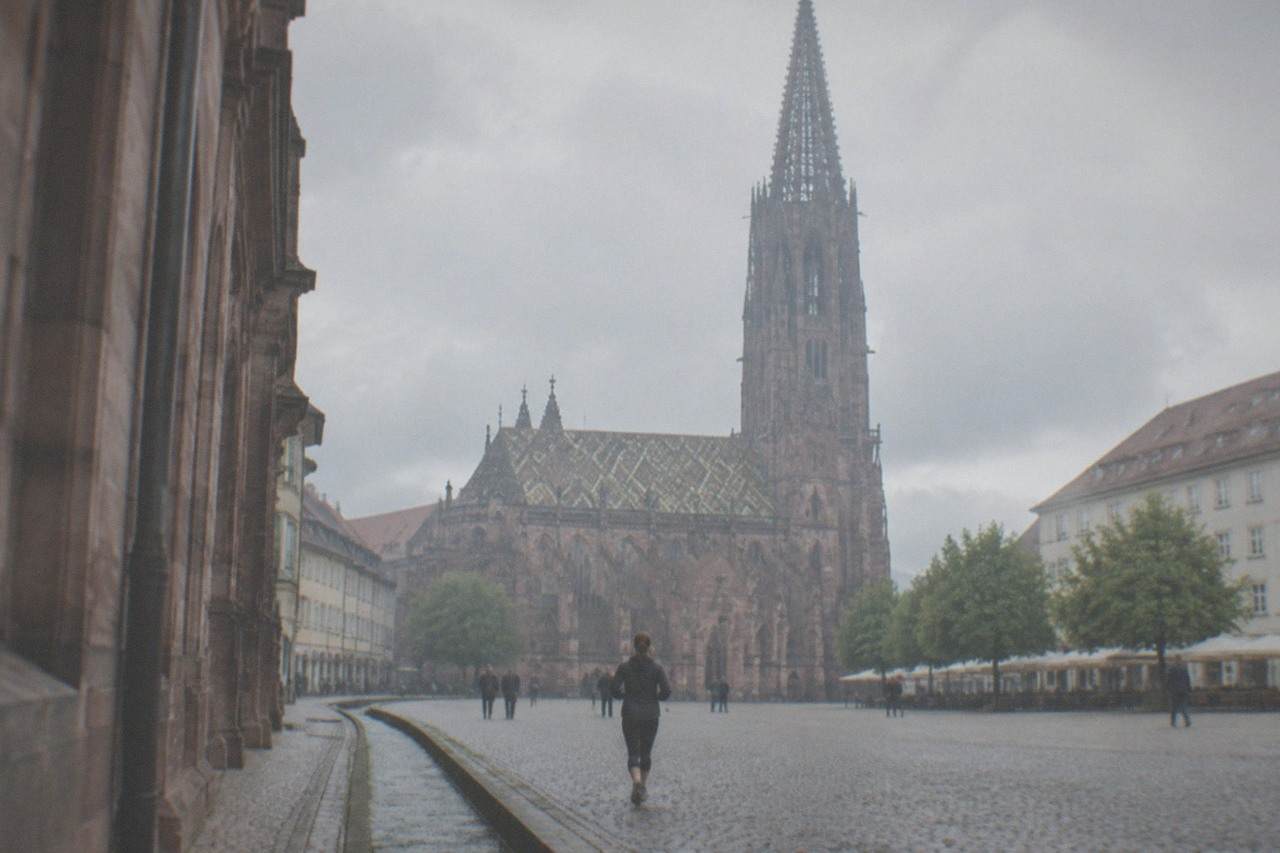 A narrow stone-lined water channel running beside the curb of a cobbled Freiburg street