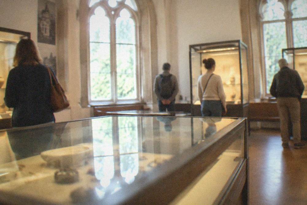 Visitors viewing display cases in a warmly lit museum gallery inside the villa