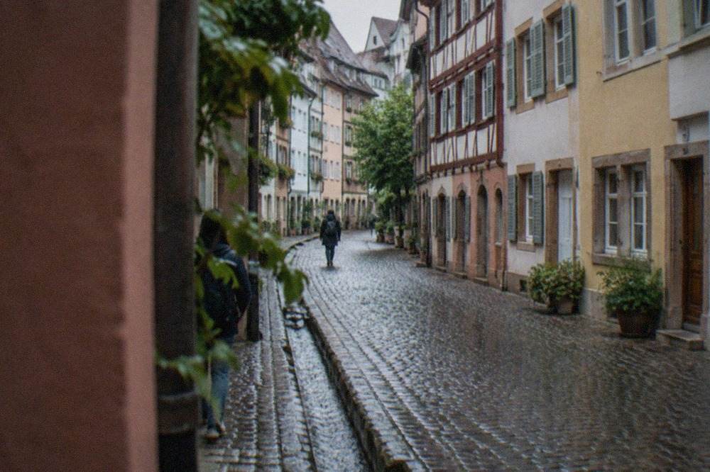 Cobbled lane with a narrow water channel beside the curb and painted half-timbered facades