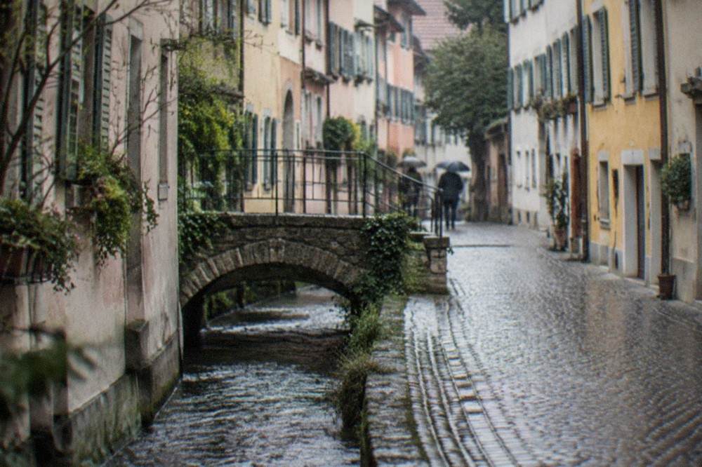 Small stone bridge over a stream beside an old lane with worn cobblestones