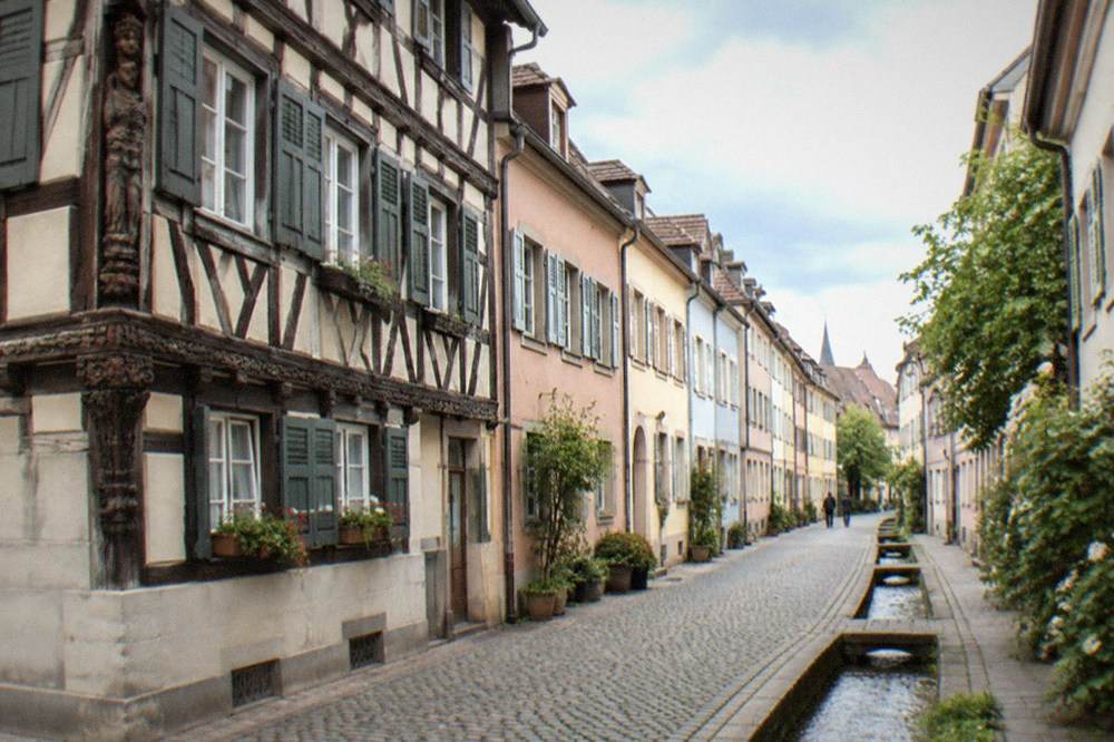Half-timbered house facade with carved wooden sign hanging over a narrow street