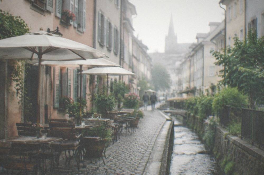 Stream channel running beside a cobbled lane with tables and chairs outside a small bar
