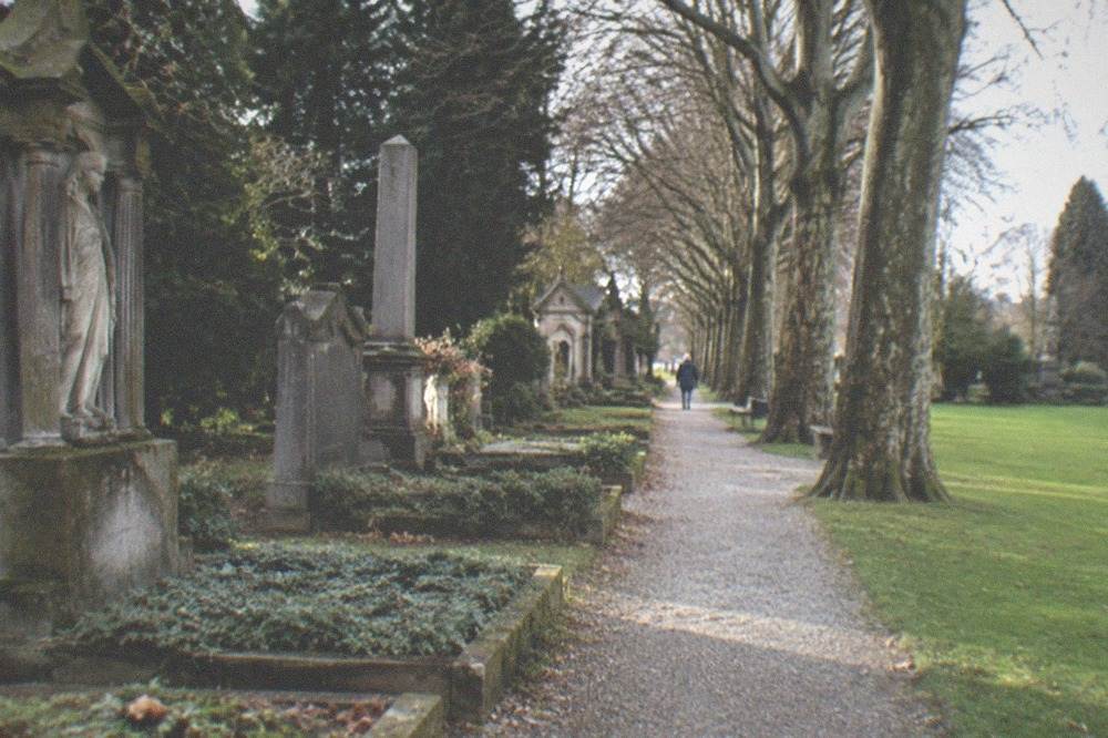 narrow gravel path between historic graves and a green lawn
