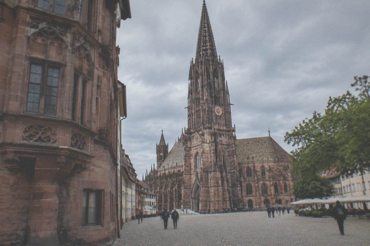 Historic red stone facade with carved bay windows on a narrow street corner in Freiburg's Old Town