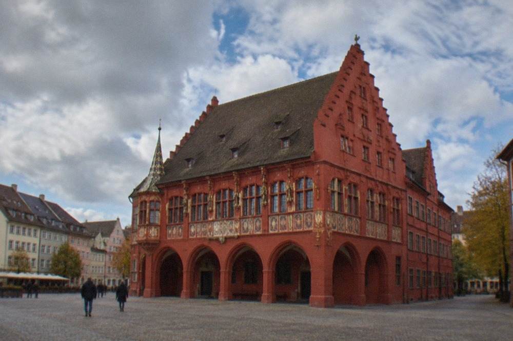 Red facade and arched arcade of the Historisches Kaufhaus on Münsterplatz in Freiburg