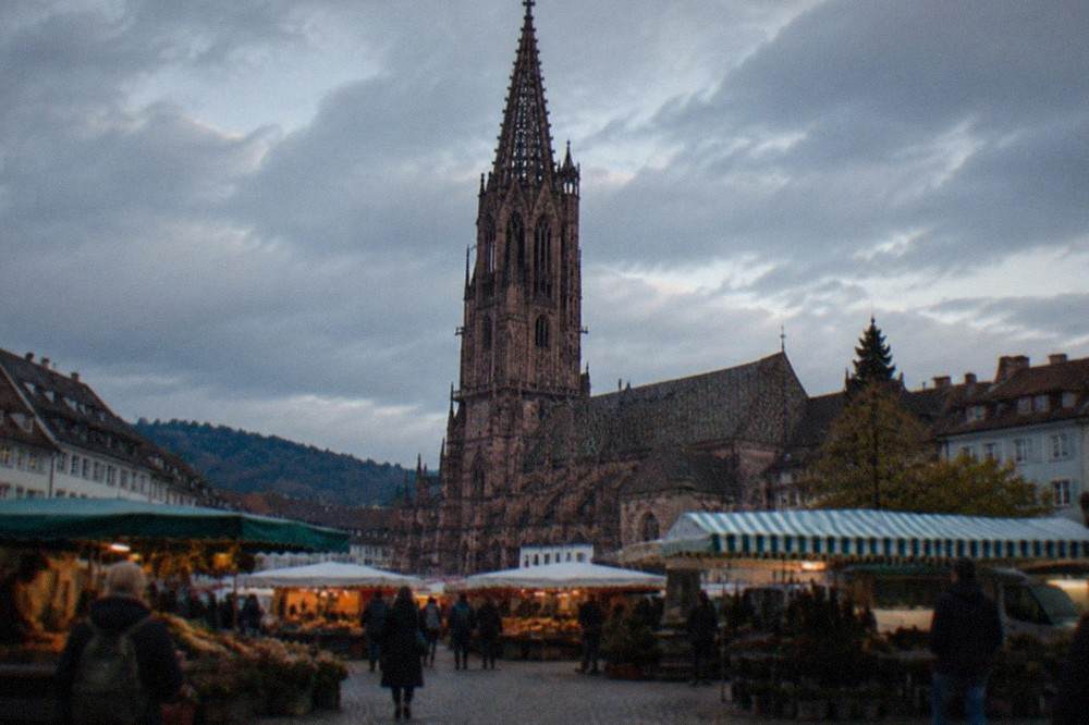 Freiburg Minster tower rising over the roofs and market stalls of Münsterplatz