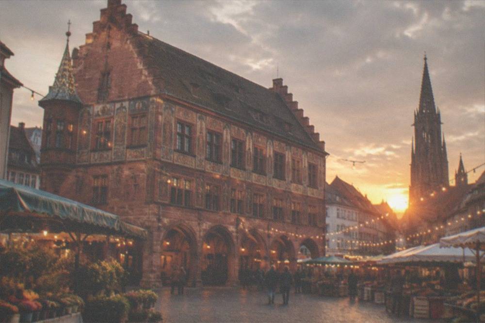 Market stalls and strings of lights above a square in Freiburg's old town at dusk
