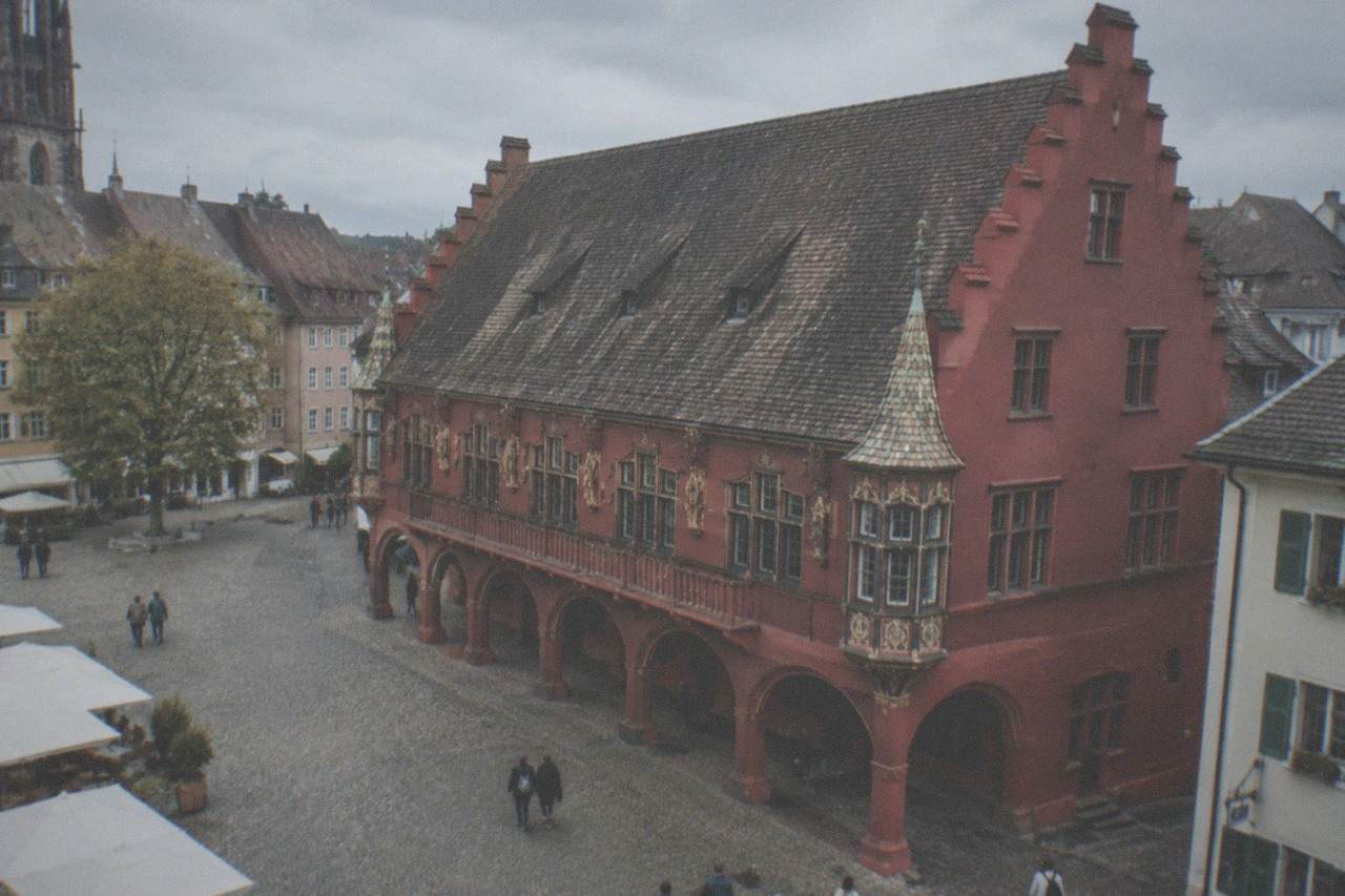 Red facade and arched arcade of the Historisches Kaufhaus on Münsterplatz in Freiburg