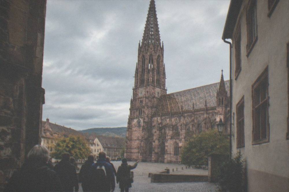 Small group of walkers following a guide along a cobbled Freiburg lane near the old town gates
