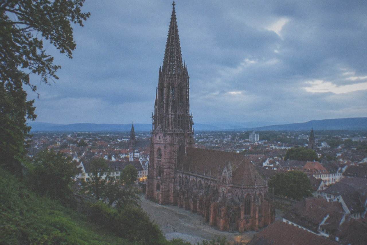 View over red rooftops of Freiburg old town from a green hillside under a blue sky