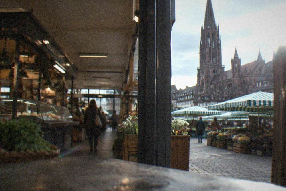 Open-air market square with striped stall awnings in front of a Gothic cathedral