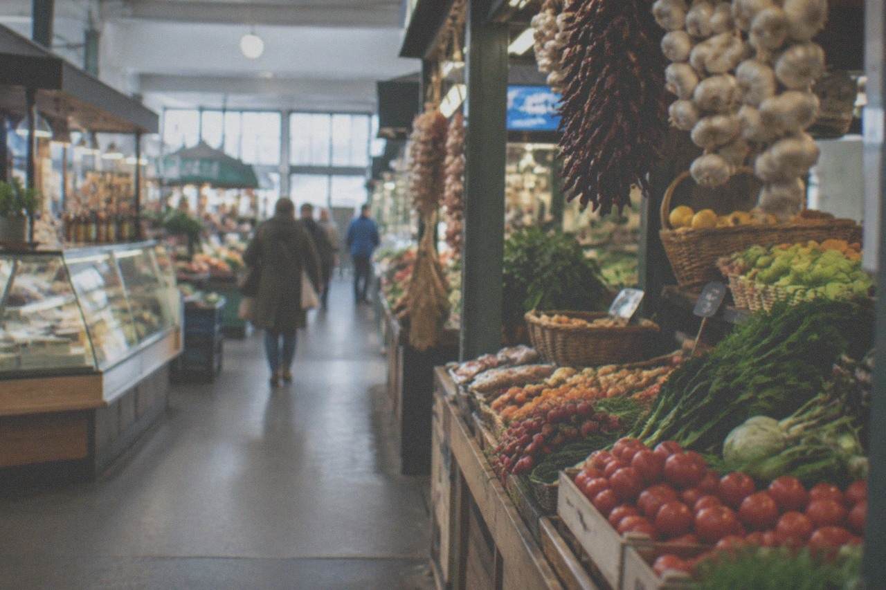 Interior of a covered market hall with food counters and hanging produce displays