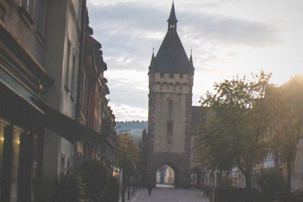 An old stone gate seen down an empty pedestrian street in early morning light