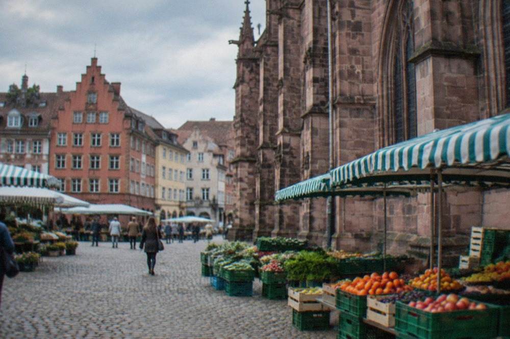 Striped market awnings and fruit crates beside the stone wall of the Minster