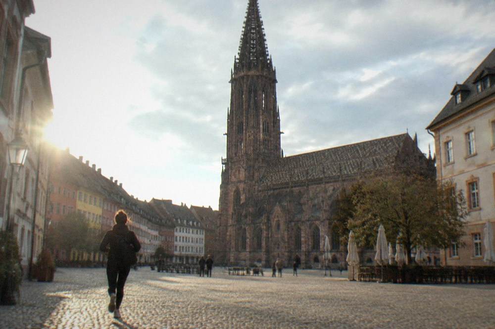 Gothic stone tower of the Freiburg Minster rising above the rooftops in clear weather