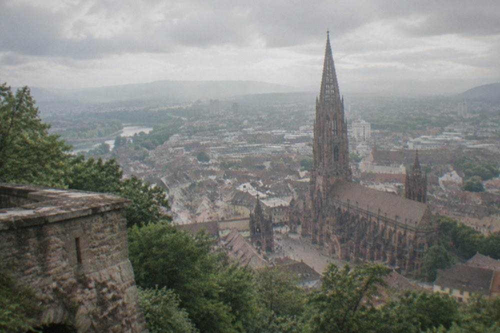 Stone lookout tower on a wooded hilltop overlooking the rooftops and cathedral spire of Freiburg