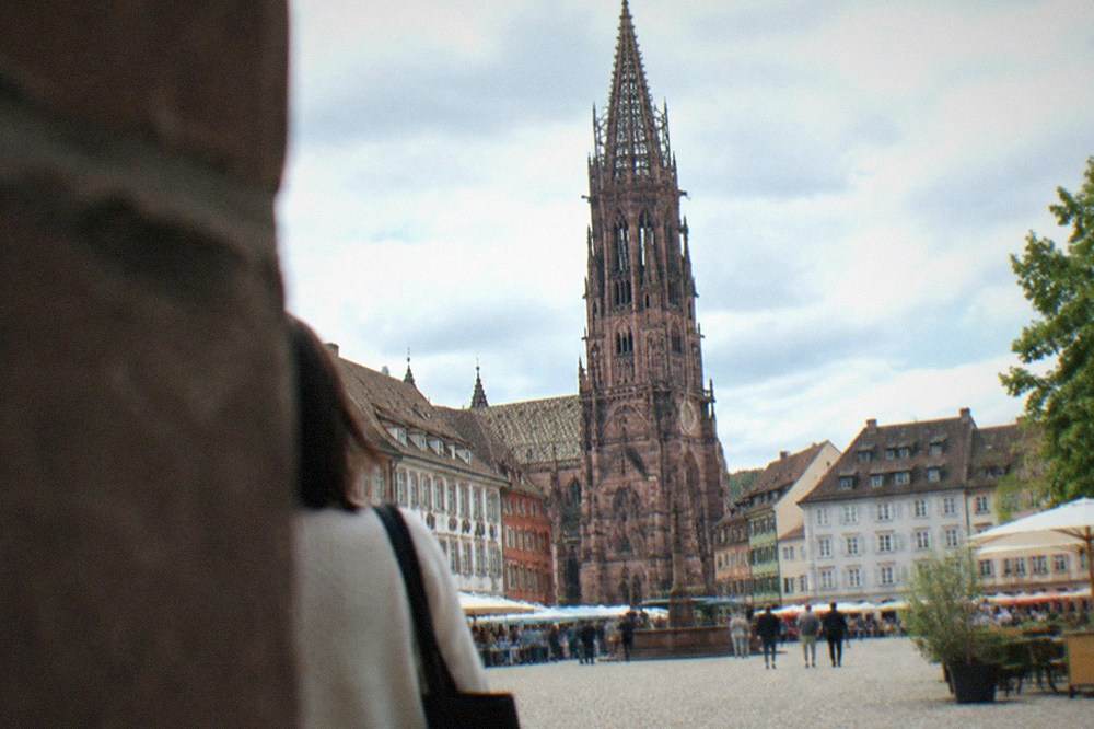 Cathedral tower rising above old town rooftops seen from a market square