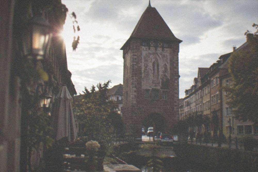 Old town lane with outdoor tables and lanterns beside a water channel