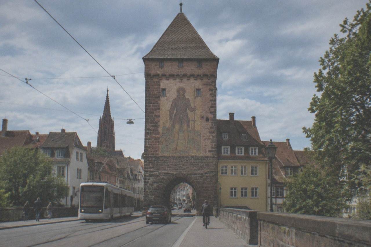 The Schwabentor gate tower rising above old town rooftops with tram tracks in the foreground