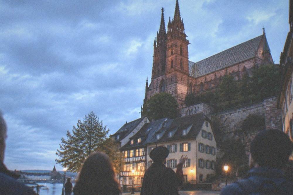 A costumed guide leading an evening walking tour through a lamplit old town square