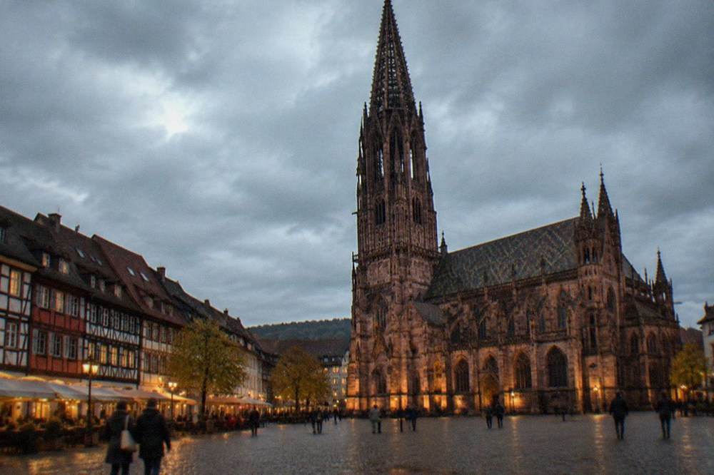 A lit square with timbered buildings in Freiburg after dark