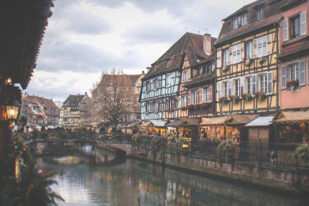 Festively lit half-timbered buildings and market stalls at dusk in Colmar