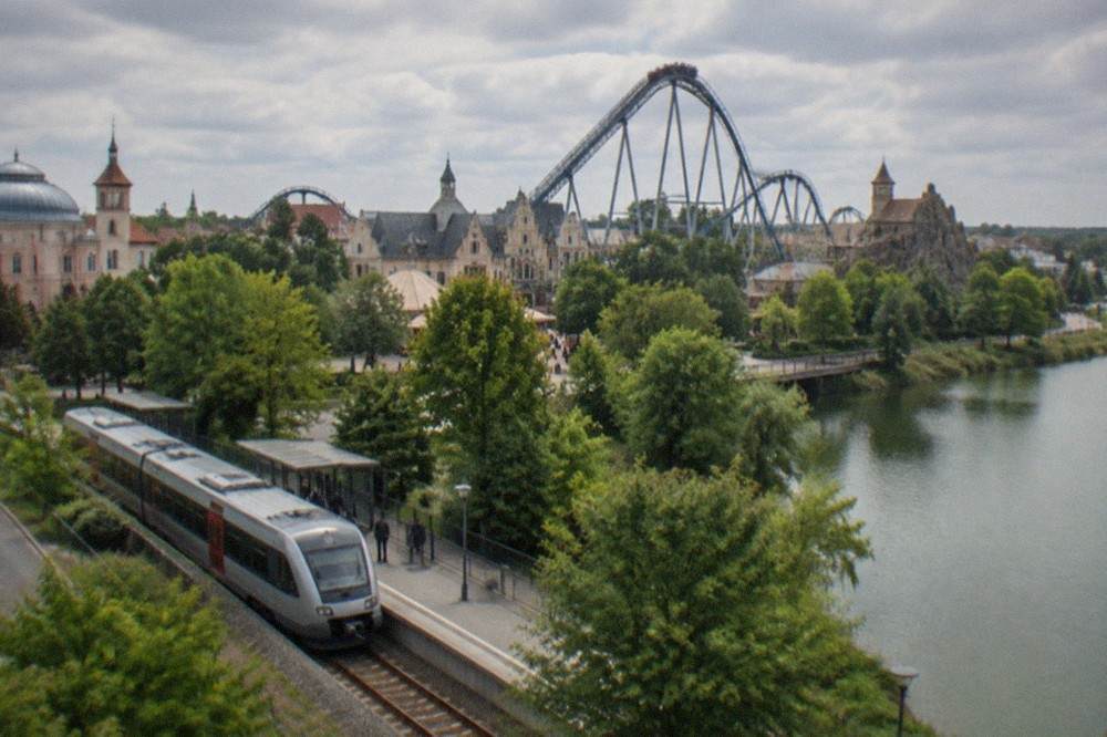 A regional train stopping at a small country station next to a theme park access road