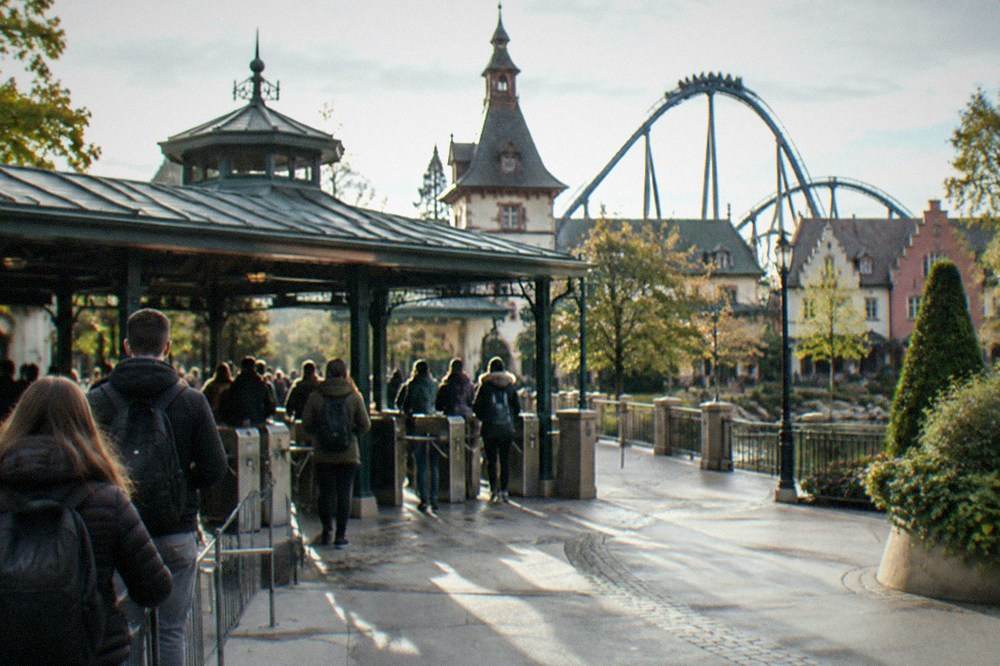 Ticket gate turnstiles at a theme park entrance with visitors waiting in morning light