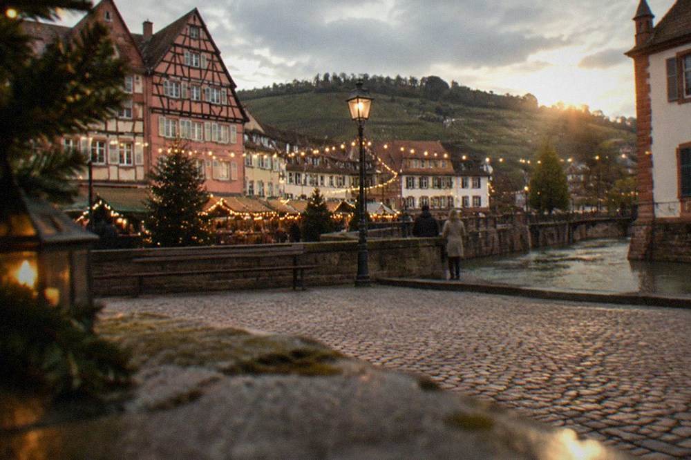 A small old town square with festive lights at dusk