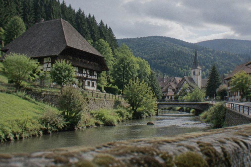 A quiet Black Forest village street with timbered houses and a church tower beyond the rooftops
